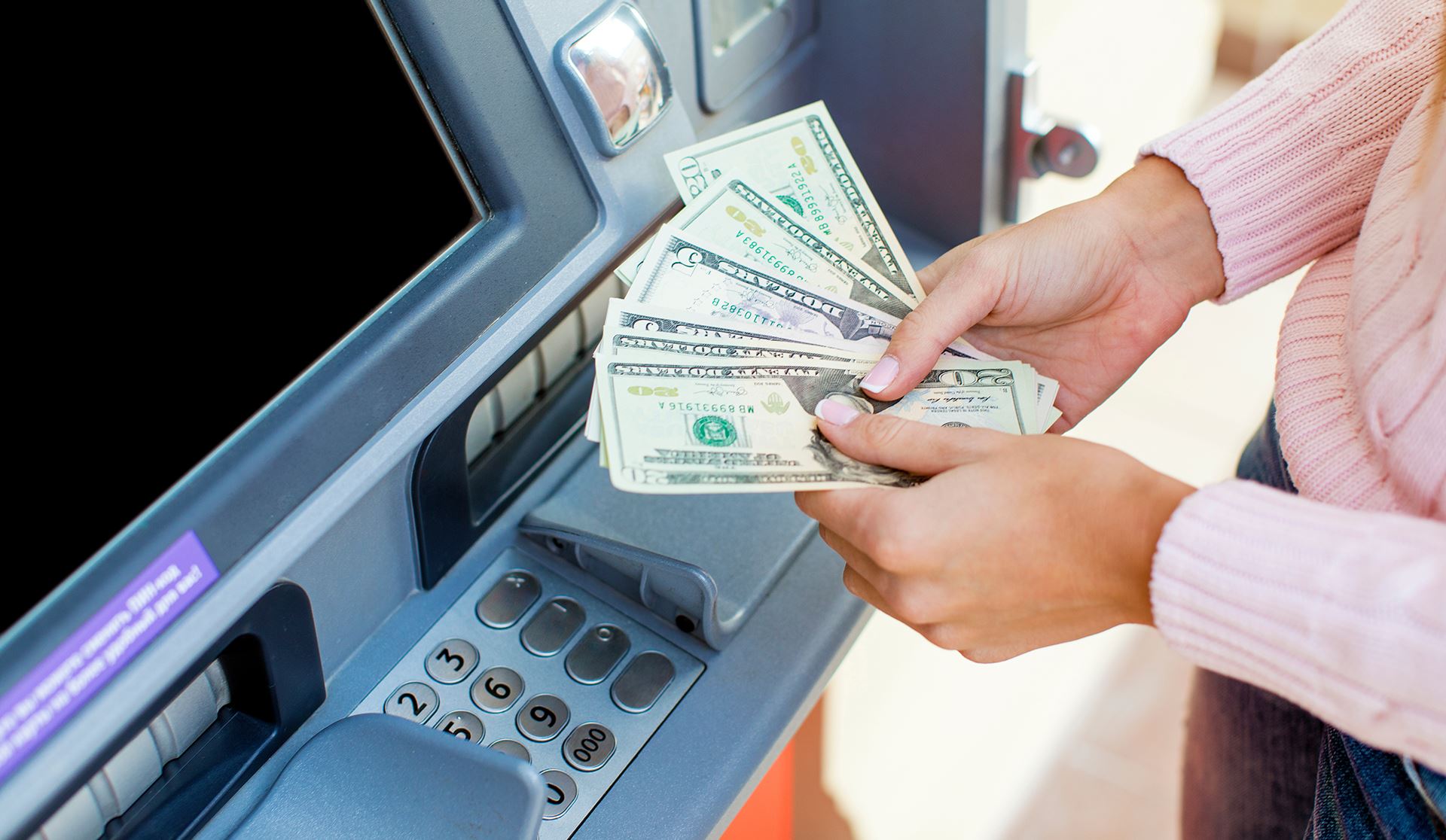 person holding cash at an ATM